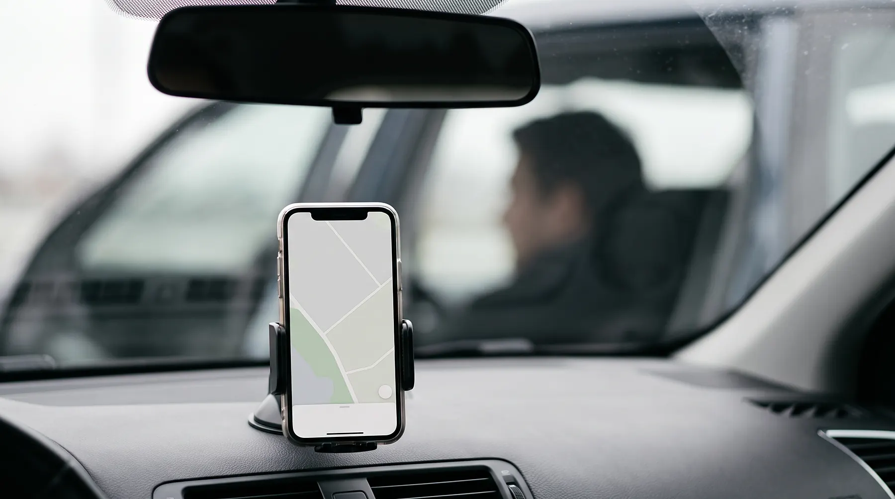 Smartphone mounted on a car dashboard showing a blank navigation map